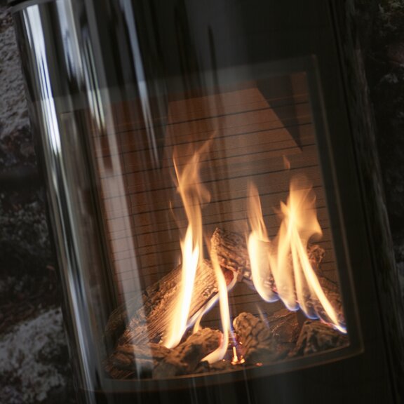 Feuerraum vom Gas-Kaminofen VIVA L mit Vollglas-Feuerraumtür und hochwertigen Holzscheit-Imitaten aus Keramik