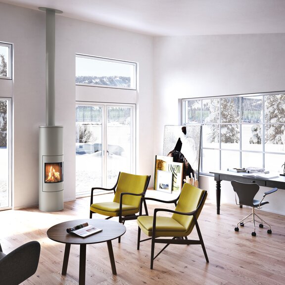 Gas-Kaminofen VIVA 160 L in Nickel mit Stahltür im Büro mit grossen Fenstern umgeben von schneebedeckter Winterlandschaft