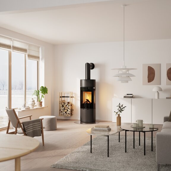 Holz-Kaminofen CARO 130 in Schwarz mit Vollglas-Feuerraumtür und Seitenfenster im Wohnzimmer mit vielen Pflanzen