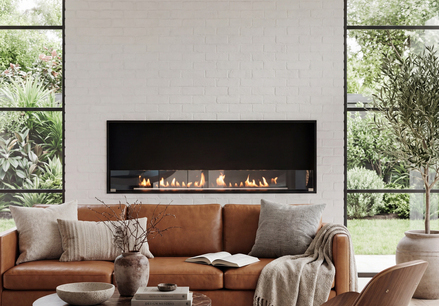Montreal Front Bioethanol Feuerstelle in Wohnzimmer mit braunem Ledersofa eingebaut in heller Steinwand