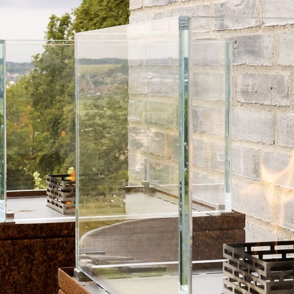 Bioethanol Feuerstelle Nice auf rostfarbener Stahlsäule an Steinwand im Garten 